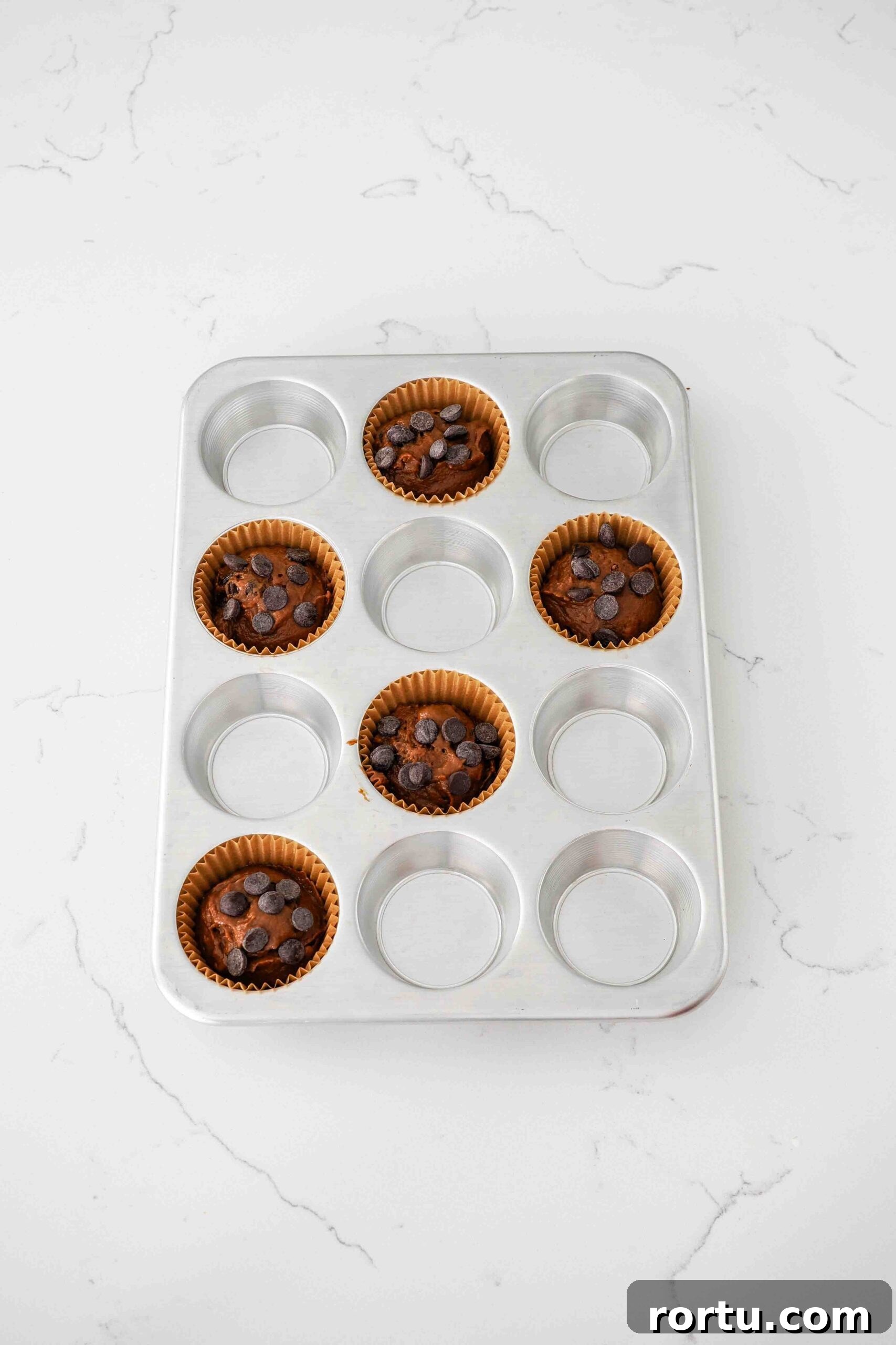 Chocolate Pumpkin Muffins Recipe — Moist Spiced Chocolate Muffins 9 Chocolate pumpkin muffins in paper muffin cups and topped with extra chocolate chips.