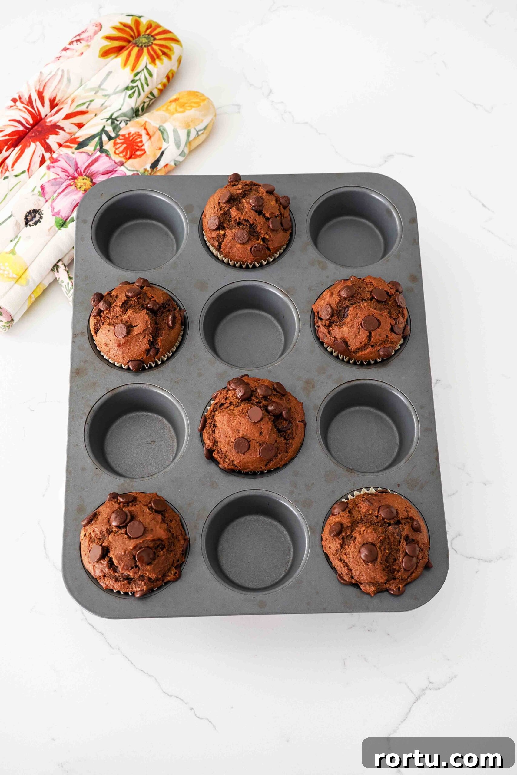 Chocolate Pumpkin Muffins Recipe — Moist Spiced Chocolate Muffins 10 Fully baked large chocolate pumpkin muffins in a dark muffin pan.