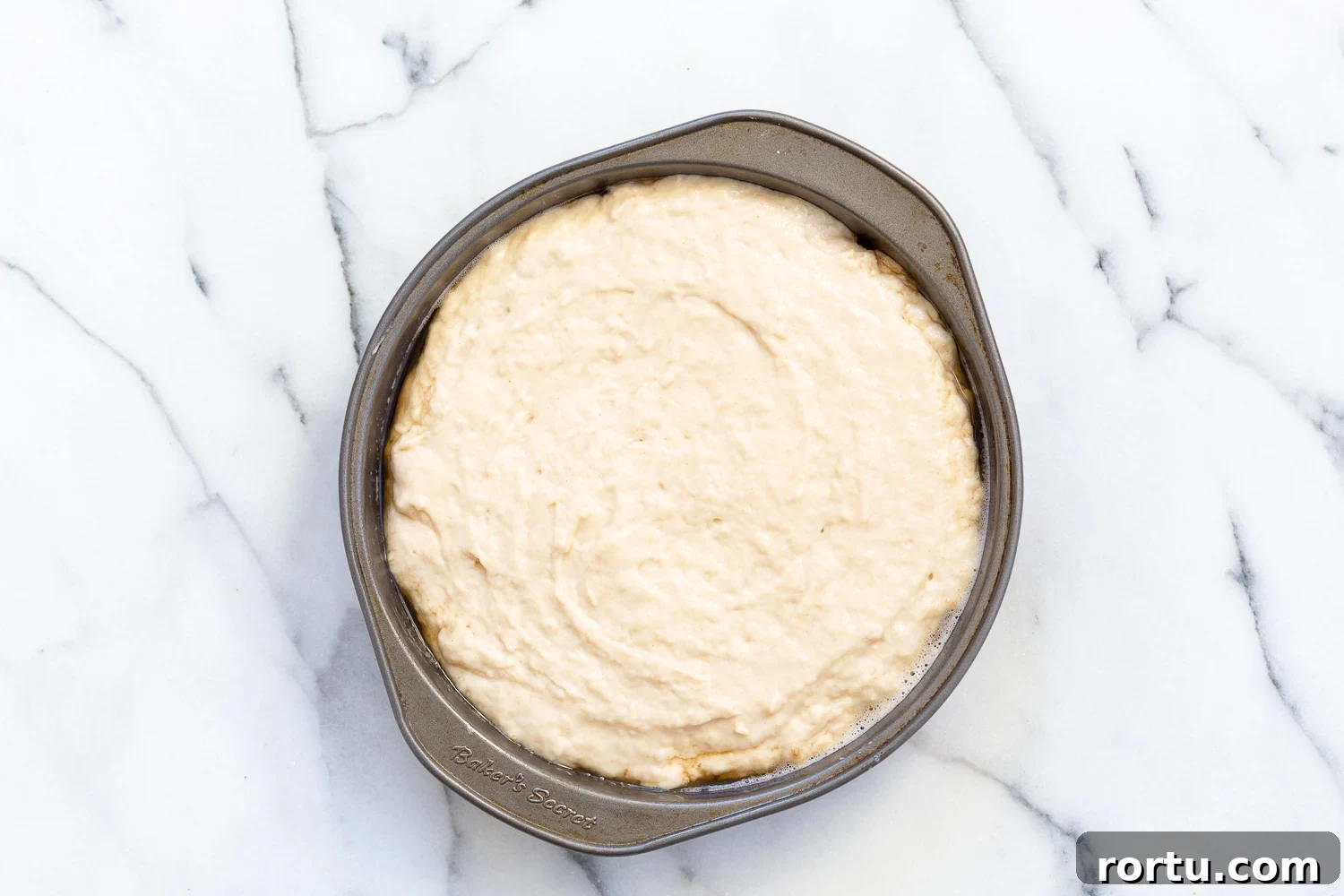 Cake Batter over pear slices in a metal cake pan for Our Vegan Pear Upside Down Cake