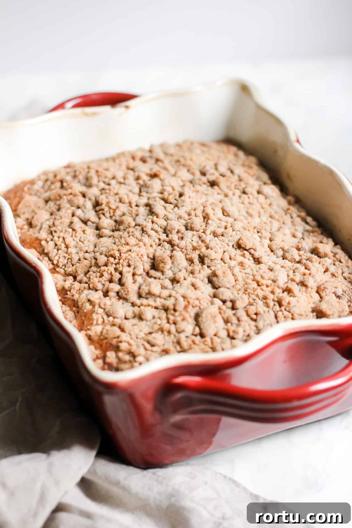 Healthier Breakfast Apple Cake with Cinnamon Sugar Crumble Topping and Maple Glaze in a Baking Dish