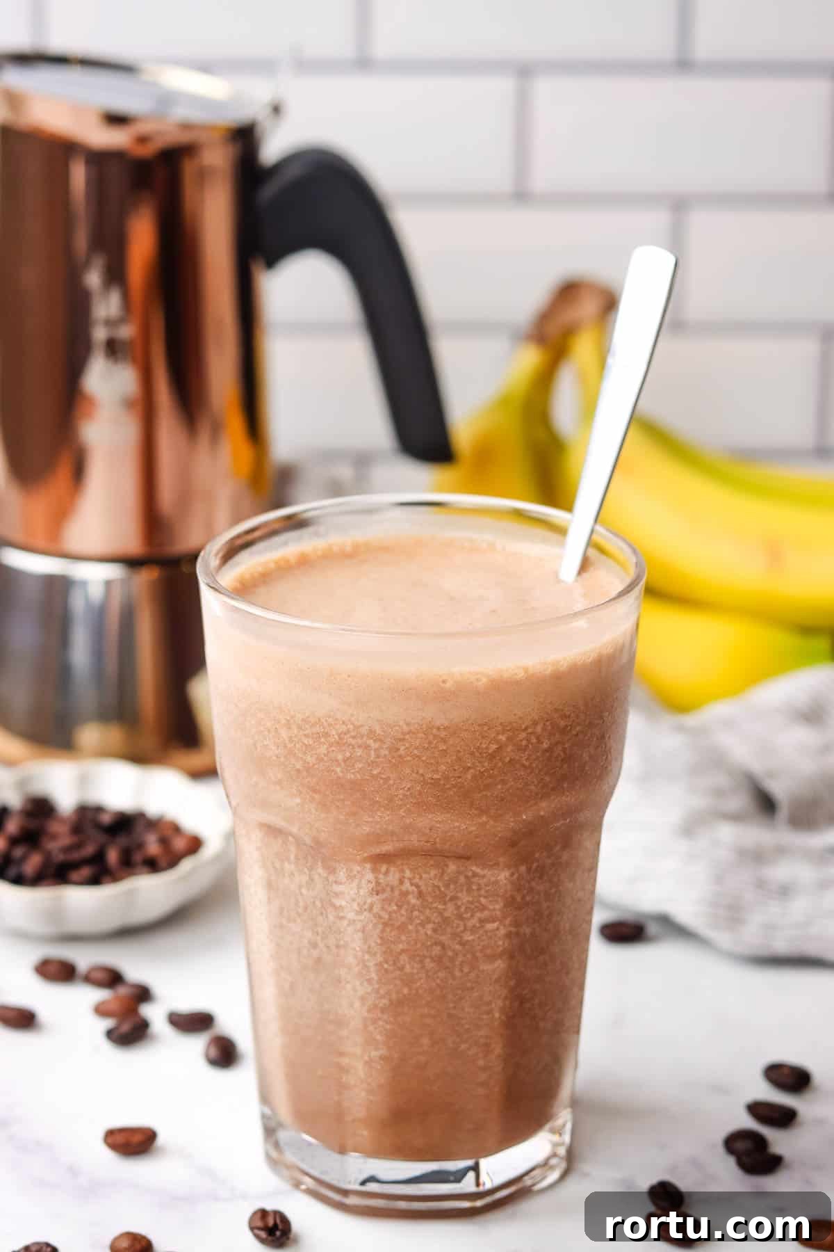 Energizing Banana Coffee Smoothie Recipe for Morning Boost 8 A tall glass of coffee banana smoothie with a spoon in it.