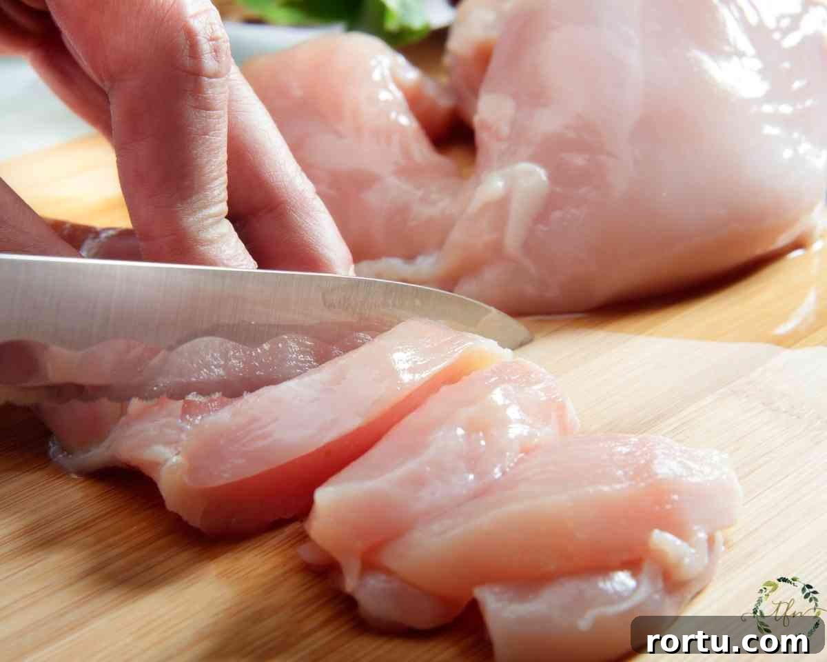 cutting chicken breast into chicken tenders strips.