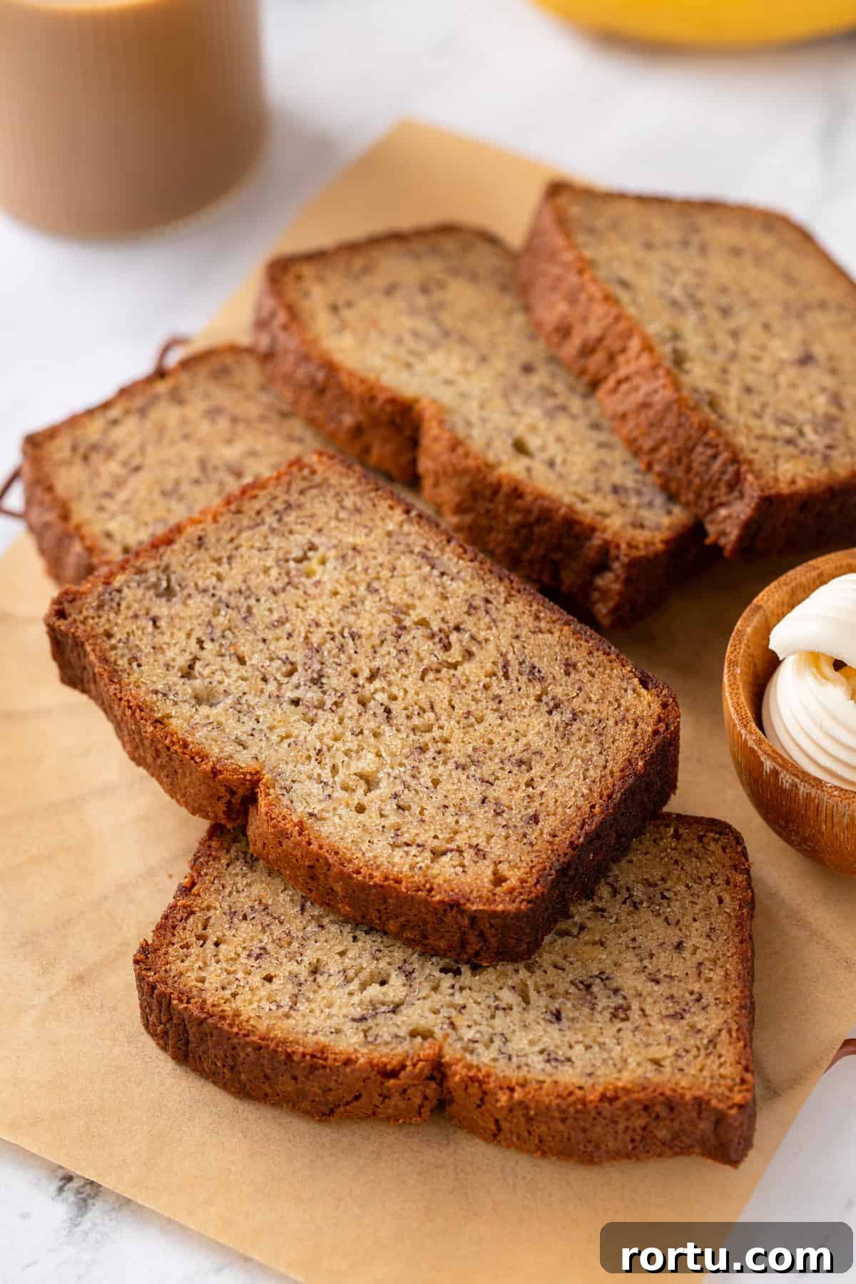 Several slices of dominique ansel's banana bread scattered on a piece of parchment paper.