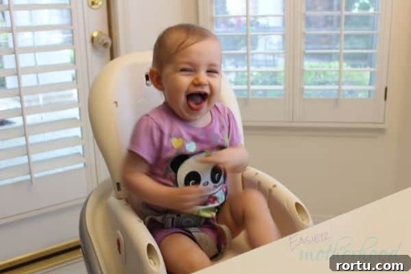 Little girl laughing in high chair