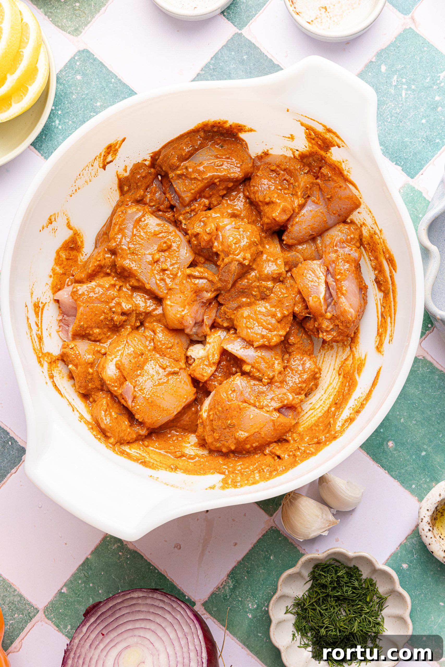 Mediterranean Sheet Pan Chicken with Lemon Garlic Yogurt Sauce 6 A large mixing bowl filled with cut up chicken thighs tossed in a spiced yogurt marinade