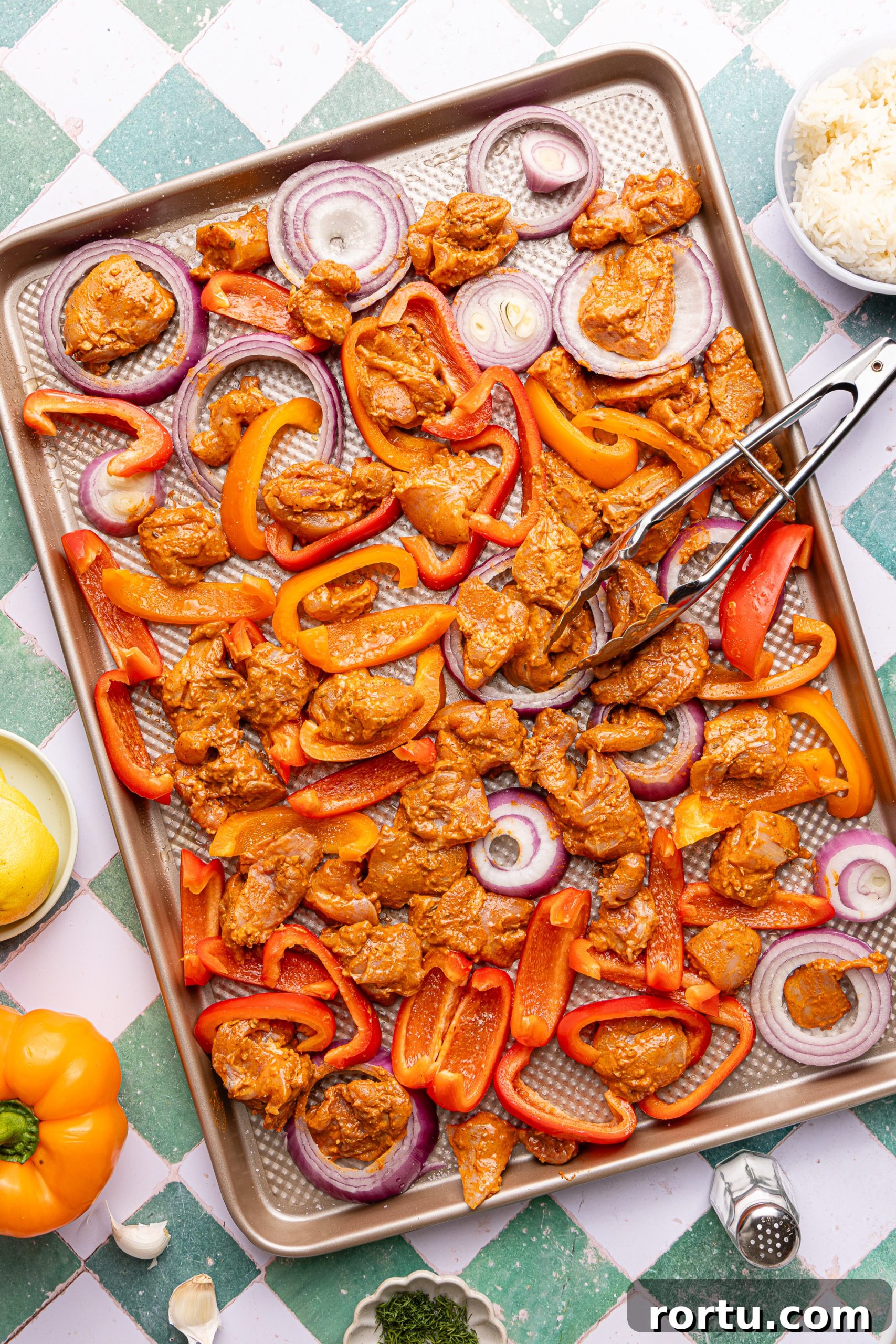 Mediterranean Sheet Pan Chicken with Lemon Garlic Yogurt Sauce 7 A large sheet pan dilled with sliced bell peppers, red onion and marinade chicken thighs ready to be baked in the oven