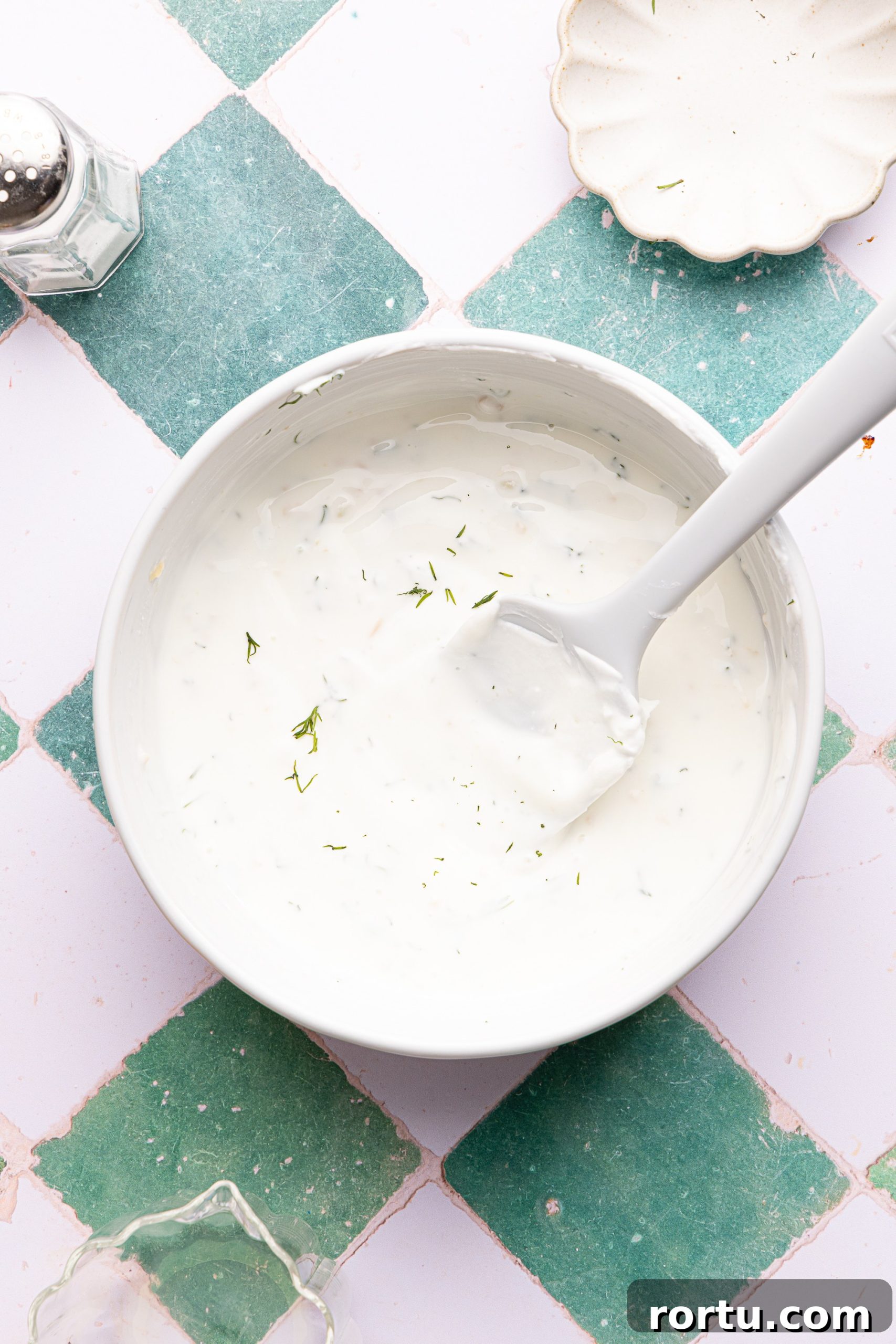 Mediterranean Sheet Pan Chicken with Lemon Garlic Yogurt Sauce 9 A small white bowl filled with creamy lemon-garlic yogurt sauce