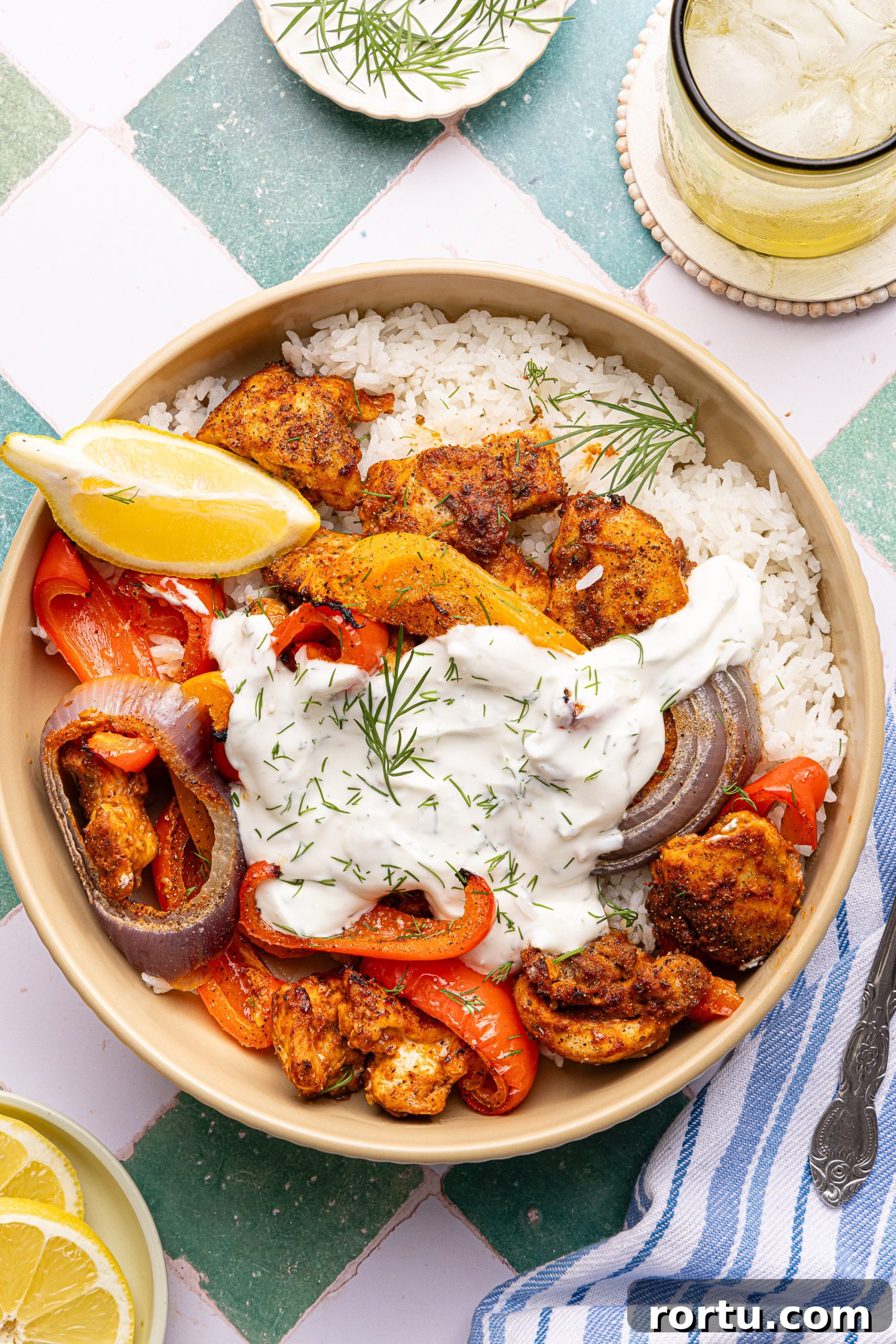 Mediterranean Sheet Pan Chicken with Lemon Garlic Yogurt Sauce 10 A bowl filled with rice and the chicken/veggies from a Mediterranean chicken sheet pan dinner