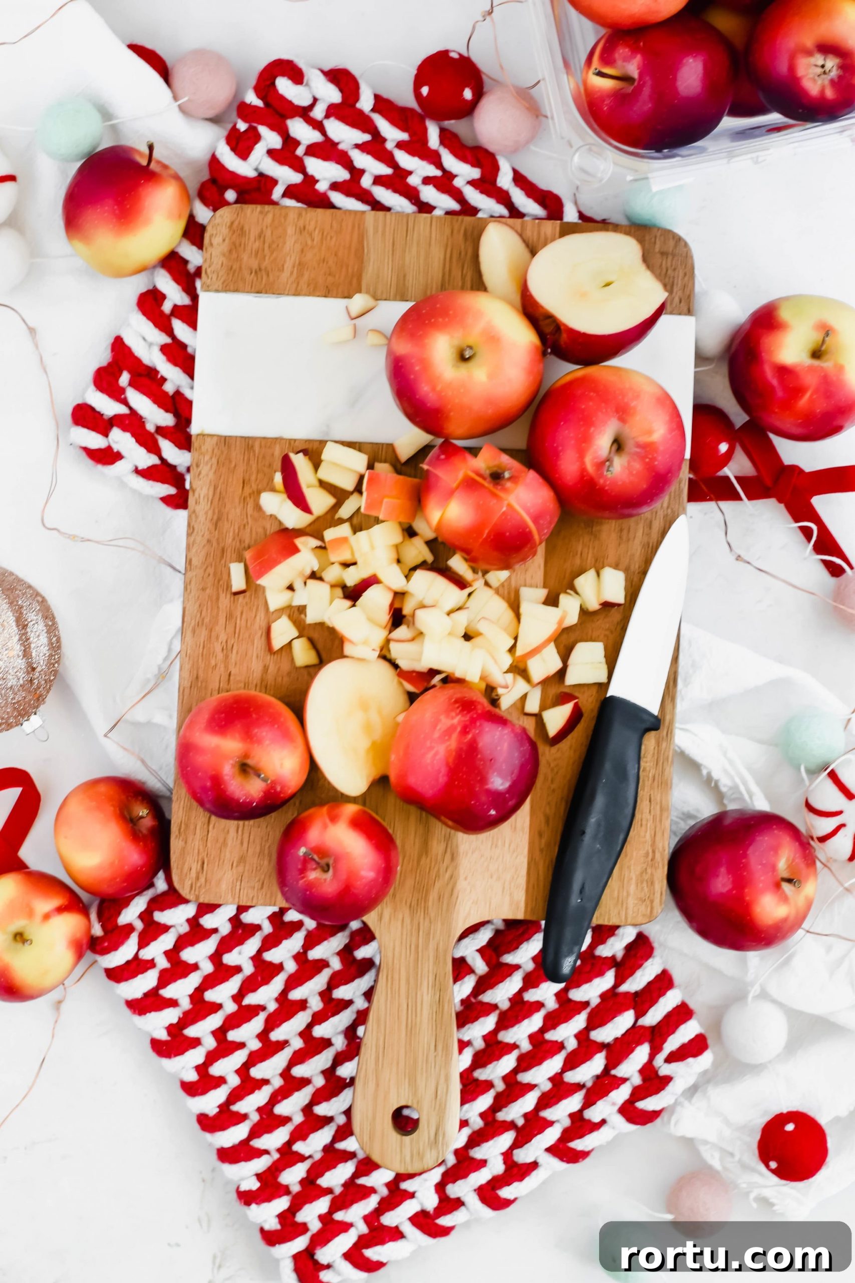 Apple Cinnamon Bites Recipe: Quick No-Bake Snack for Kids and Adults 4 chopped rockit apples on a wooden cutting board with a ceramic knife.