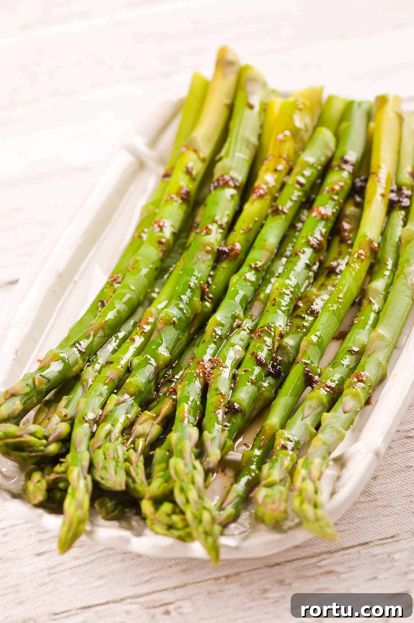 A platter of steamed asparagus drizzled with a combination of brown butter and balsamic vinegar.