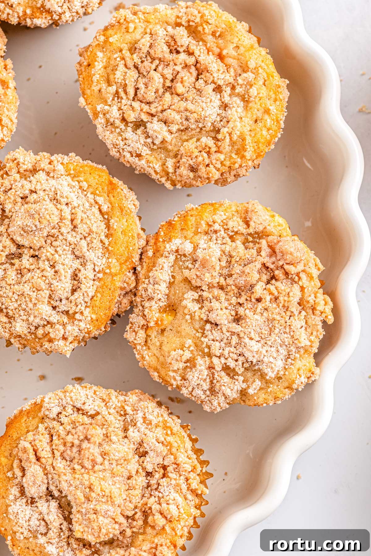 Four Apple Cinnamon Streusel Muffins on a white platter. 