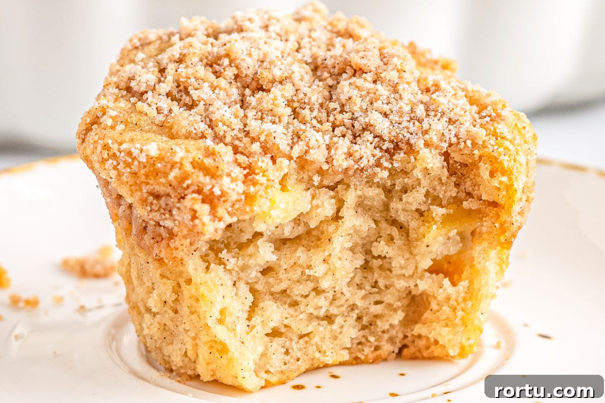 A Apple Cinnamon Streusel Muffins with a bite taken out of it so you can see the interior.