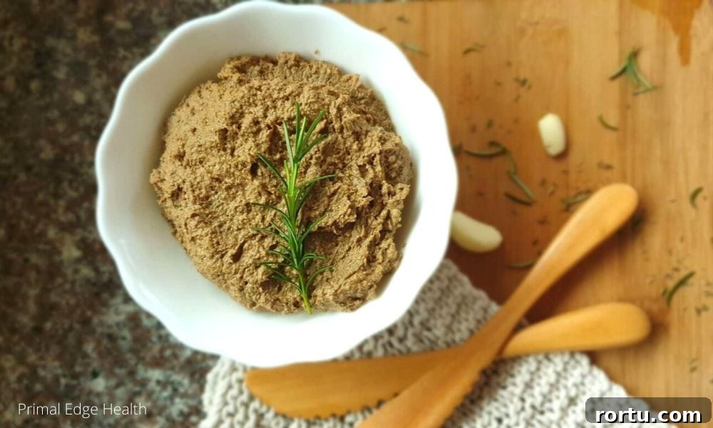 A dairy-free liver pate served in a white bowl with a sprig of rosemary.