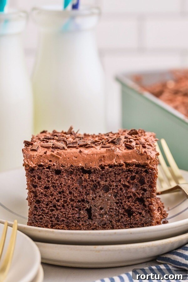 Creamy Mint Grasshopper Pie Recipe That Impresses 14 Chocolate poke cake on a plate with bottles of milk behind the plate.