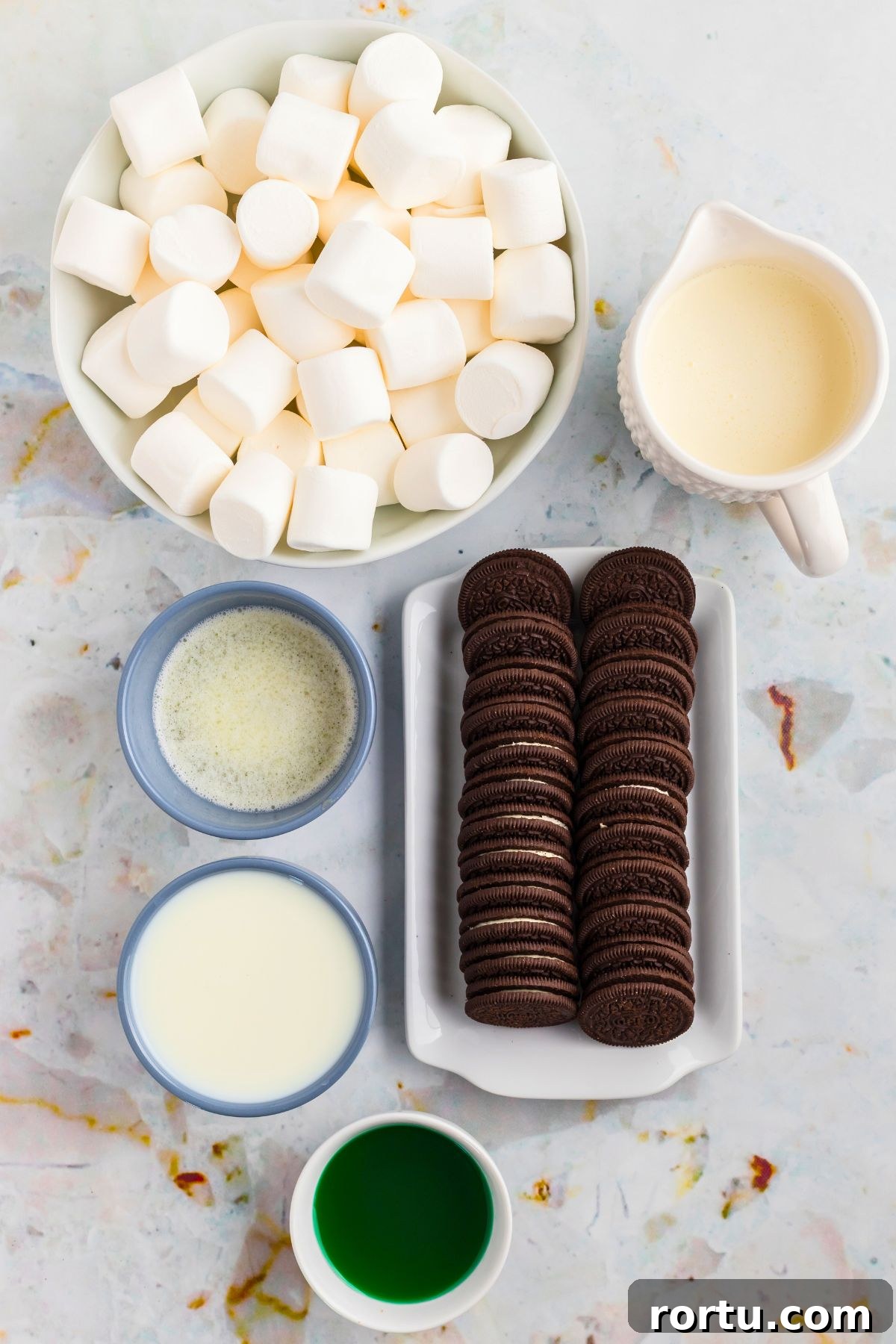Creamy Mint Grasshopper Pie Recipe That Impresses 3 Chocolate cookies, marshmallows, and other ingredients measured into small containers on a marble table.