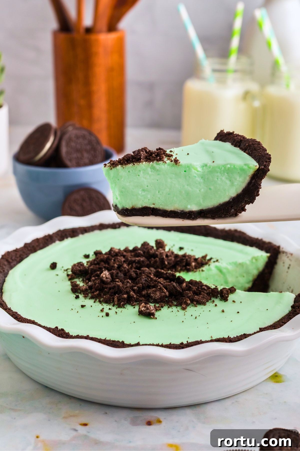 Creamy Mint Grasshopper Pie Recipe That Impresses 10 Green grasshopper pie in a white pie dish with one scoop being lifted out with a spatula.