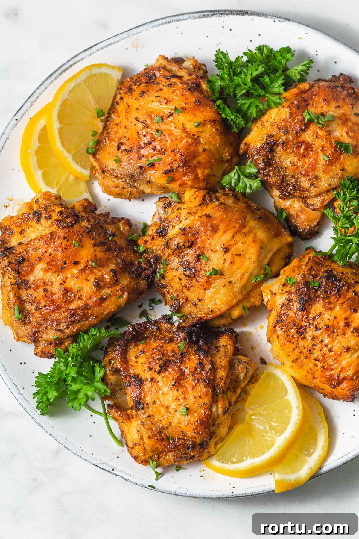 Air fryer chicken thighs with lemon slices on a plate