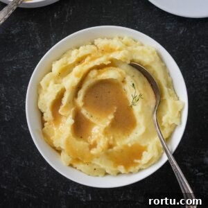 Bowl of mashed potatoes topped with vegan gravy.
