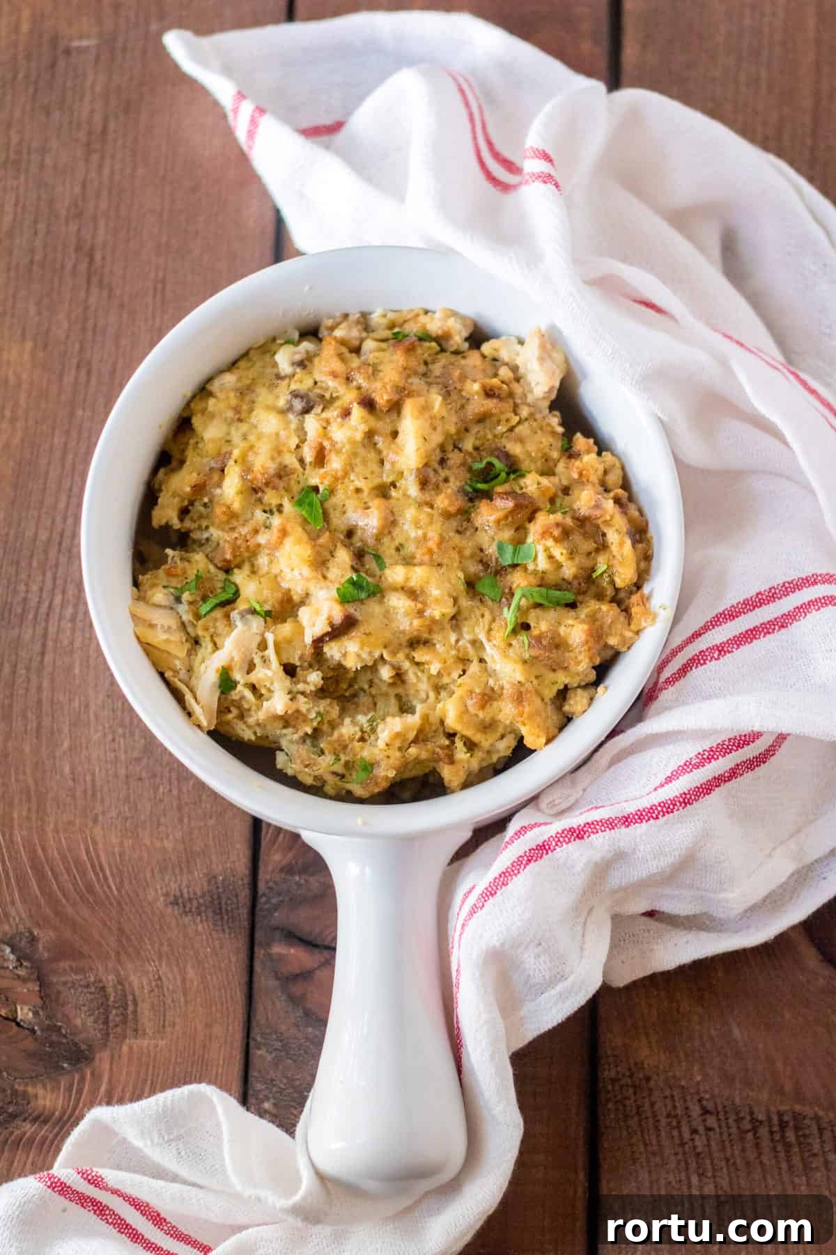 turkey stuffing served in a white soup bowl with handle sitting on a kitchen towl