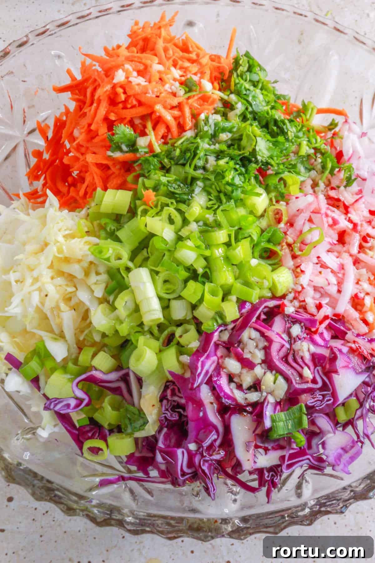 Tossing coleslaw ingredients with vinaigrette in a large bowl