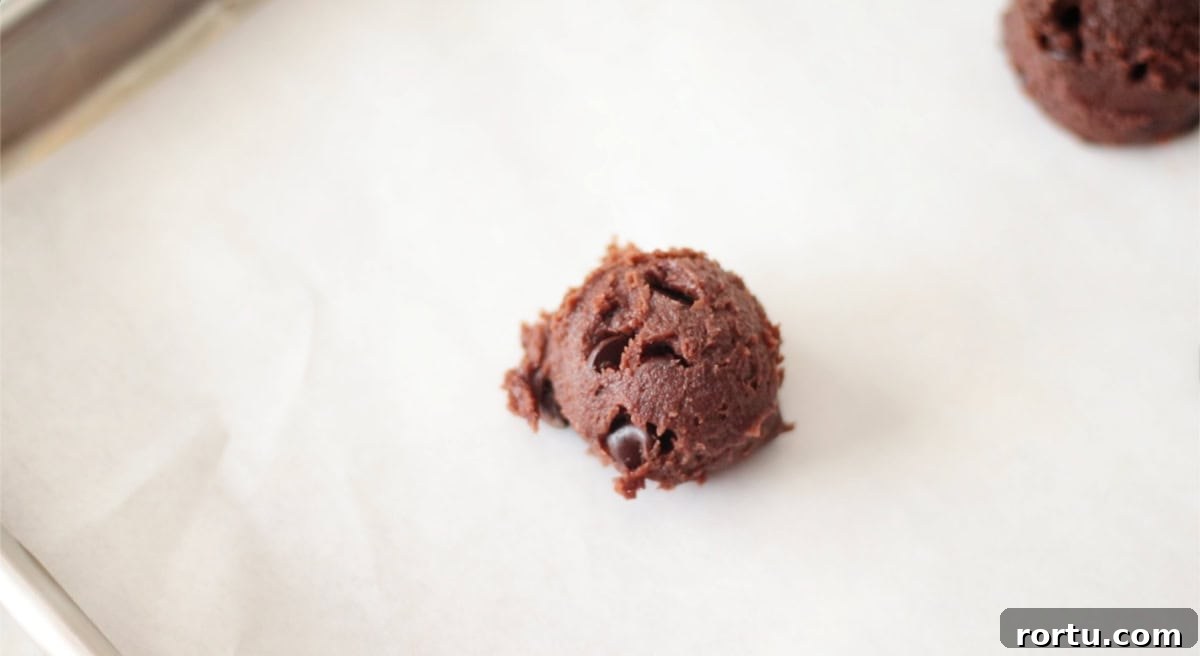 Chocolate pumpkin cookie dough on baking sheet with parchment paper.