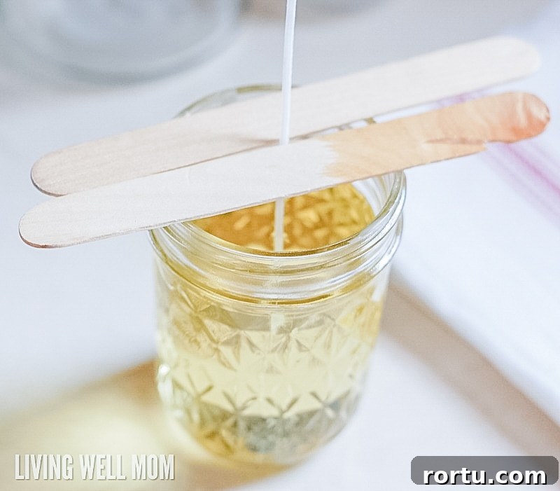 Make Homemade Citronella Candles to Repel Mosquitoes 8 popsicle sticks being used to hold up the wick in DIY citronella candles