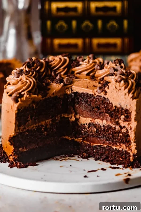 triple chocolate cake on a white plate with a large piece cut out to show the inside of the cake.