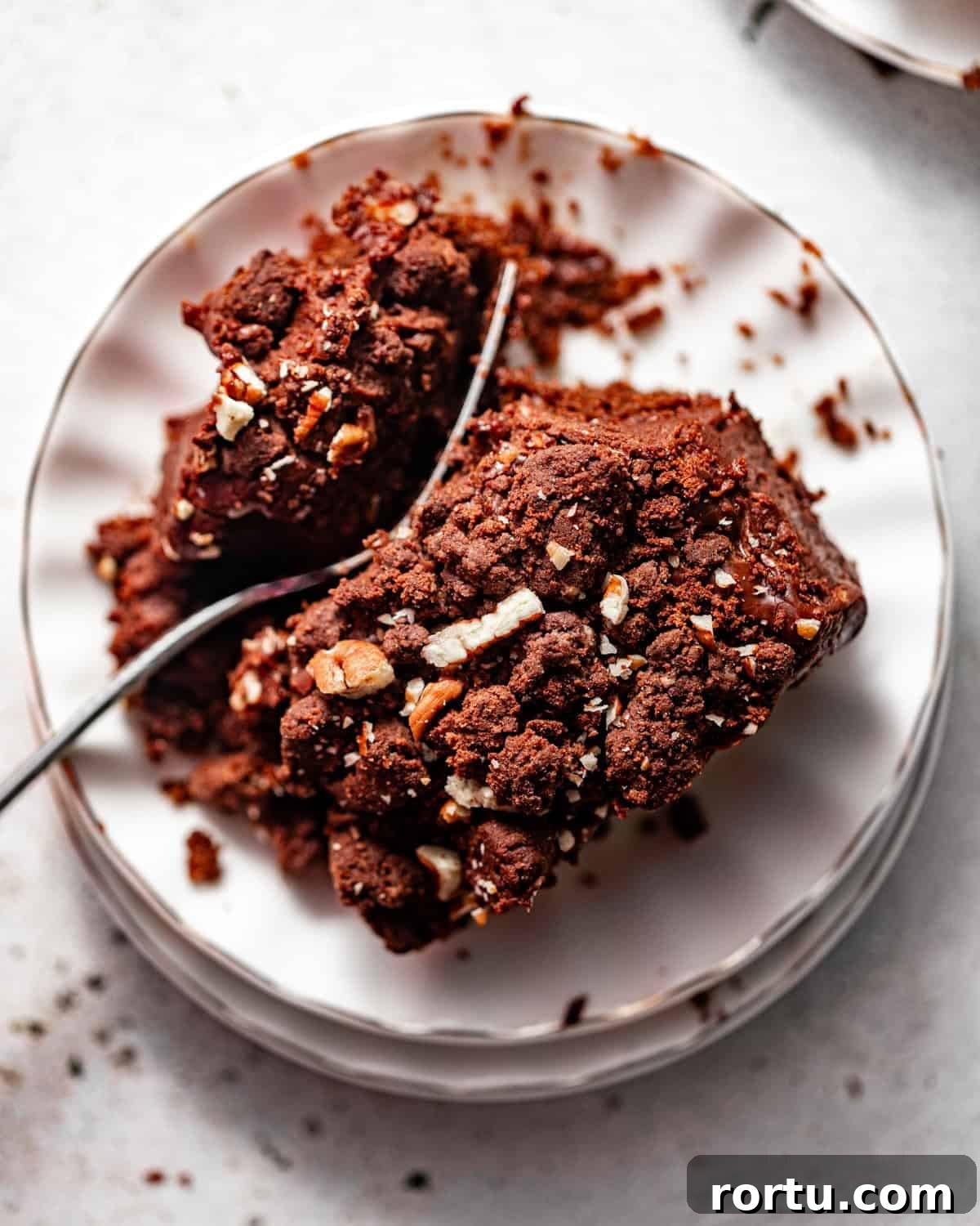 photo of texas sheet cake on a plate topped with chocolate fudge frosting and chocolate crunch topping.