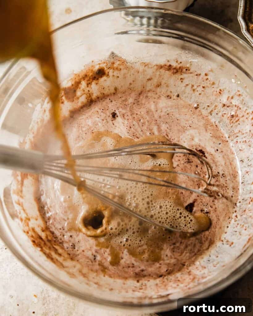 hot coffee being poured into the chocolate cake batter.