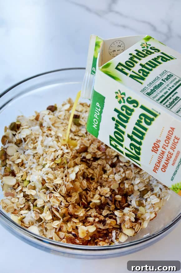 Orange Honey Granola Parfaits with Greek Yogurt and Citrus Crunch 4 A carton of orange juice being poured into a bowl with granola ingredients