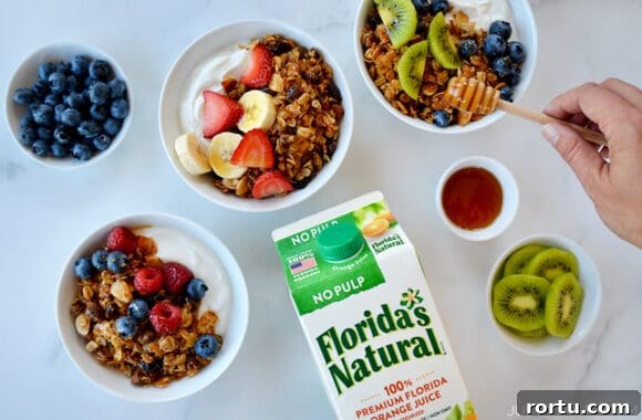 Orange Honey Granola Parfaits with Greek Yogurt and Citrus Crunch 6 A top-down view of granola parfaits in bowls and a carton of orange juice