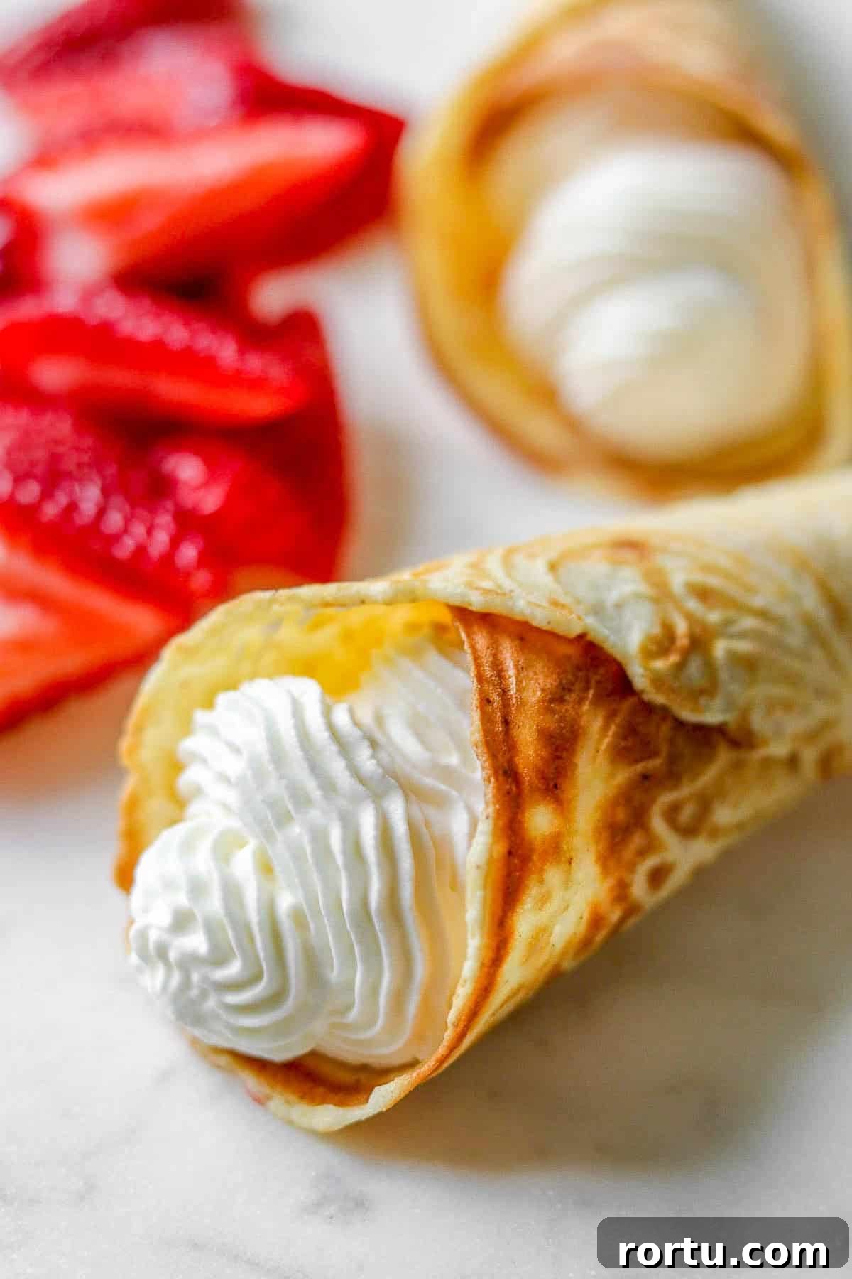 Close up of a krumkake filled with whipped cream.