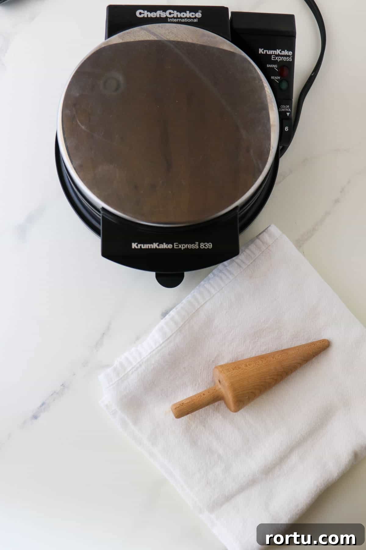 Krumkake baker with a towel and a cone form.