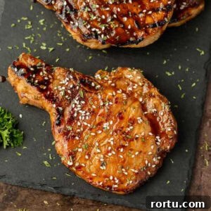 Grilled bone-in pork chops topped with sauce and sesame seeds.