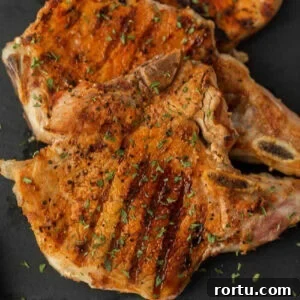 Grilled pork chops on a black slate.