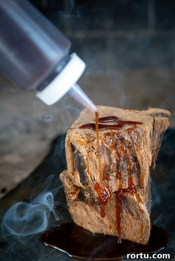 Smoked Baby Back Ribs on the Ninja FlexFlame Grill 12 Drizzling hot honey on wood with smoke in background.