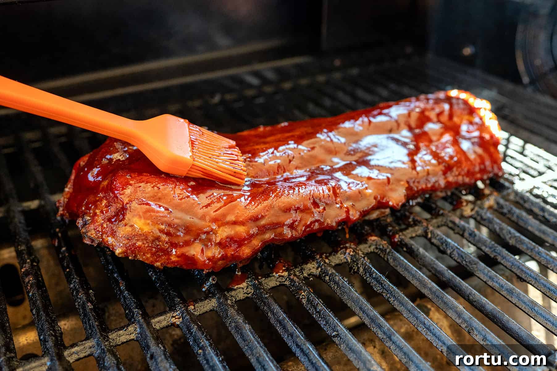Smoked Baby Back Ribs on the Ninja FlexFlame Grill 7 brushing sauce on baby back ribs.