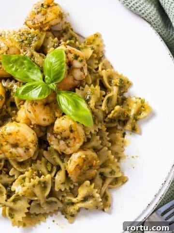 Shrimp over pesto pasta garnished with basil.