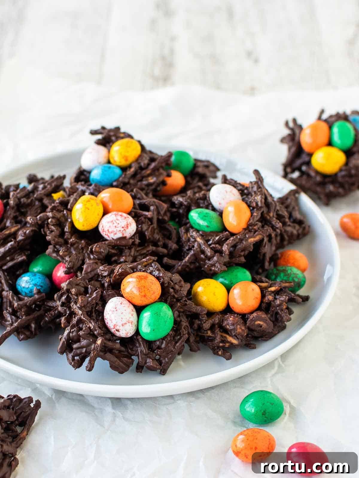 Chocolate Bird's Nest Cookies with colored candy eggs on a white plate.
