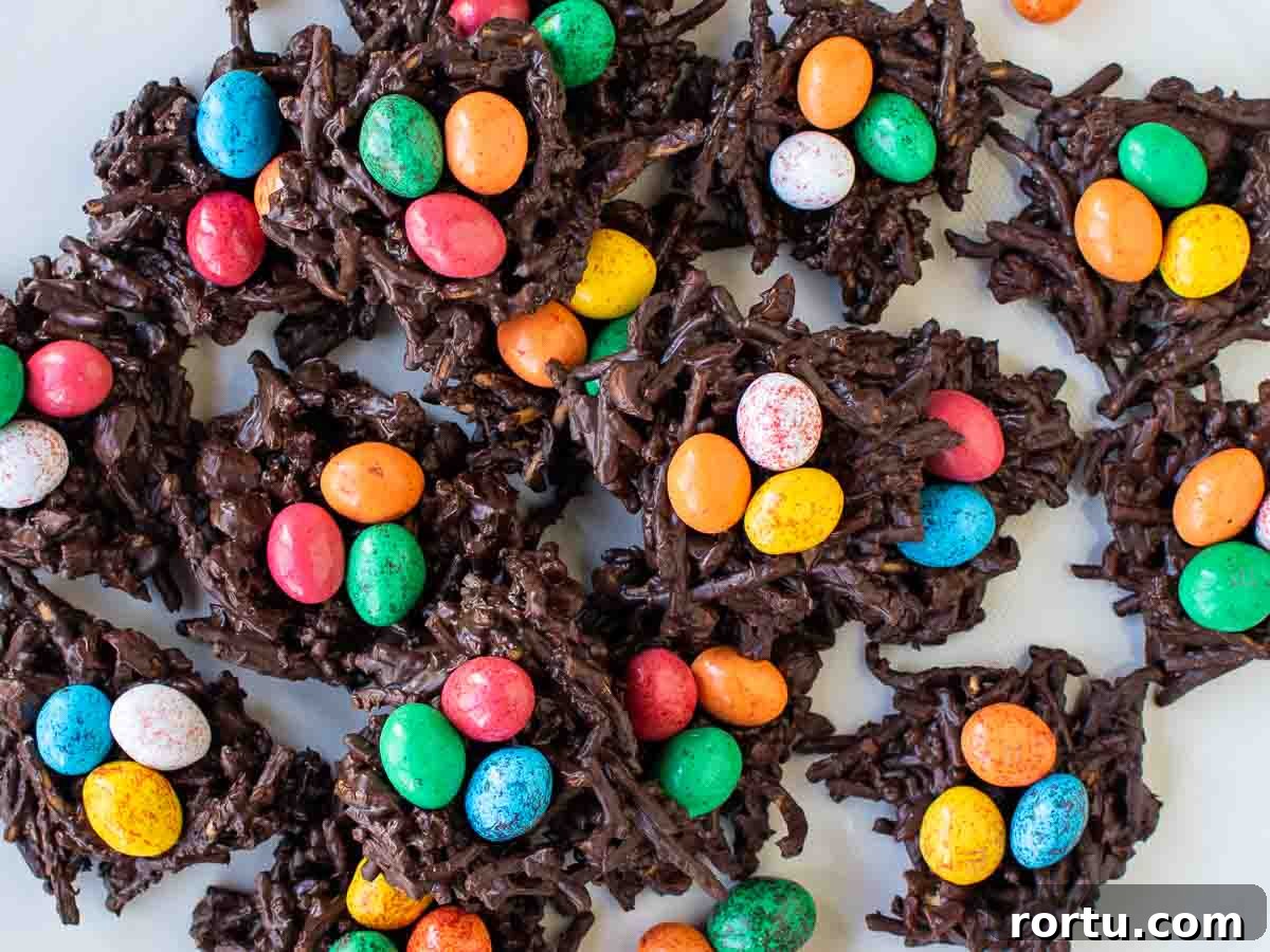 Piles of chocolate and noodles nests with candy eggs in each viewed from above.