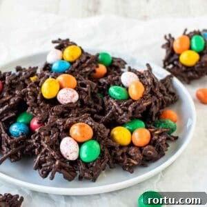 Chocolate nests with colored candy eggs on a white plate.