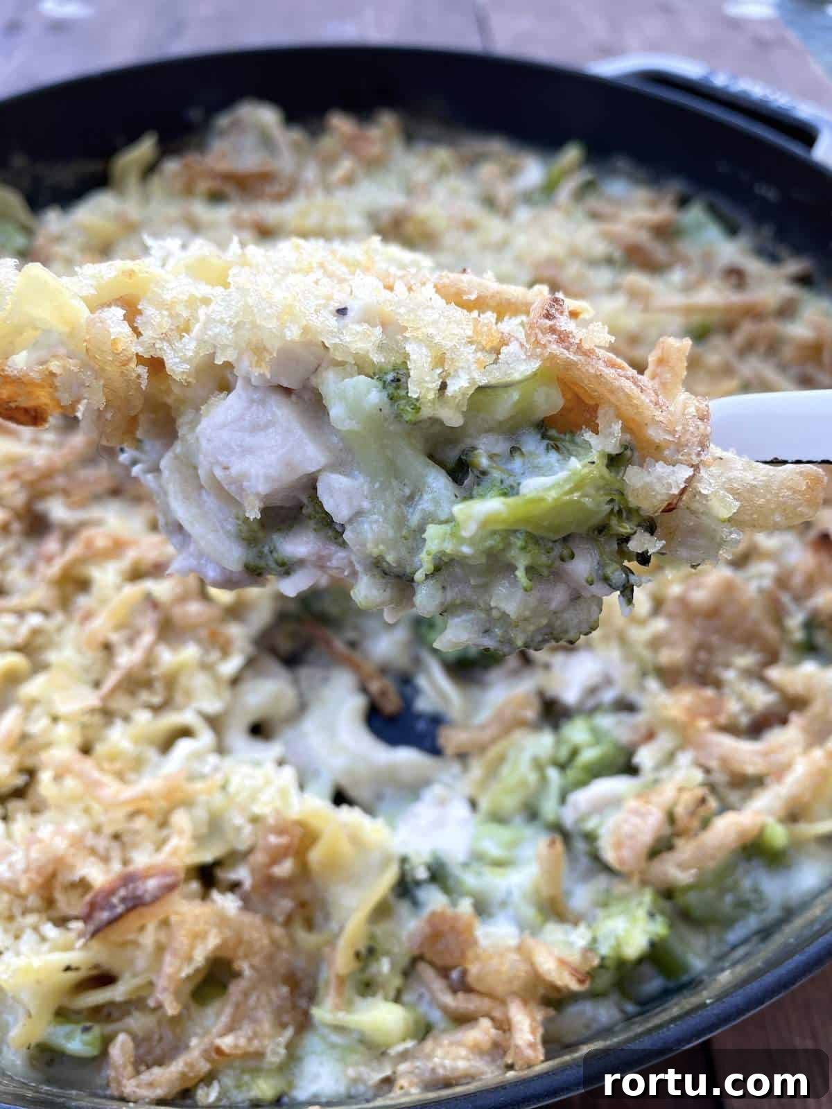 A scoop of cheesy chicken noodle casserole being served.