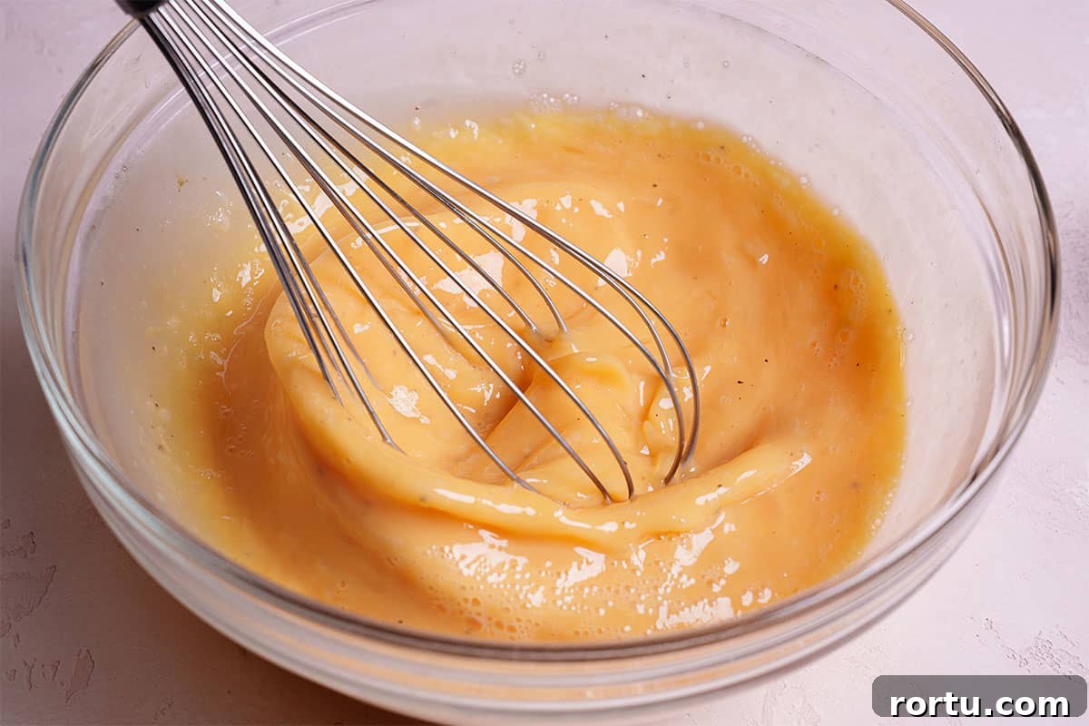 An image of eggs being whisked together in a clear bowl.