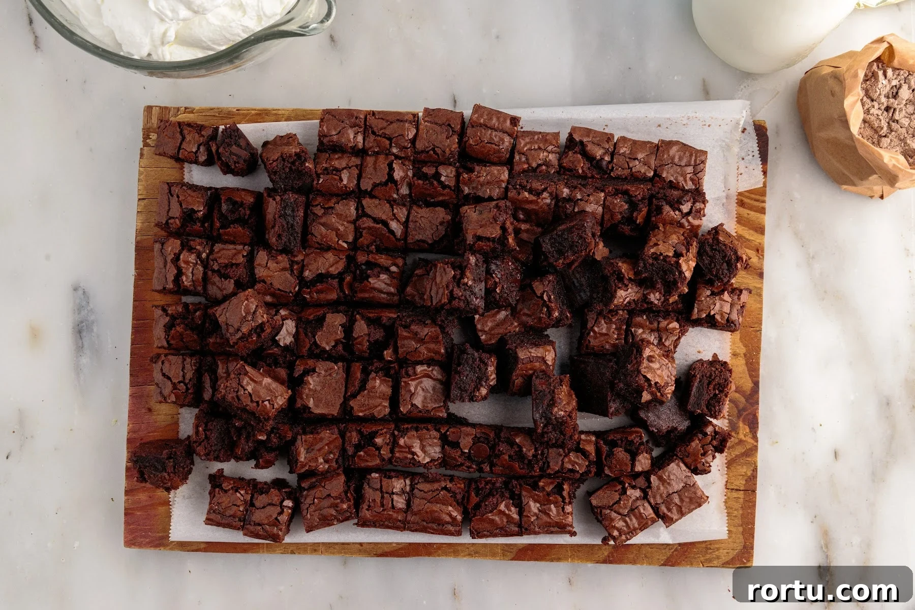 Brownies cut into squares on a wooden cutting board.