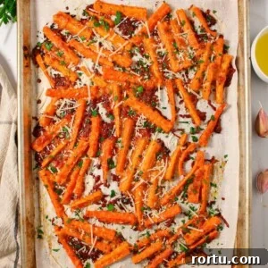 A sheet pan with crispy parmesan carrot sticks garnished with parsley.