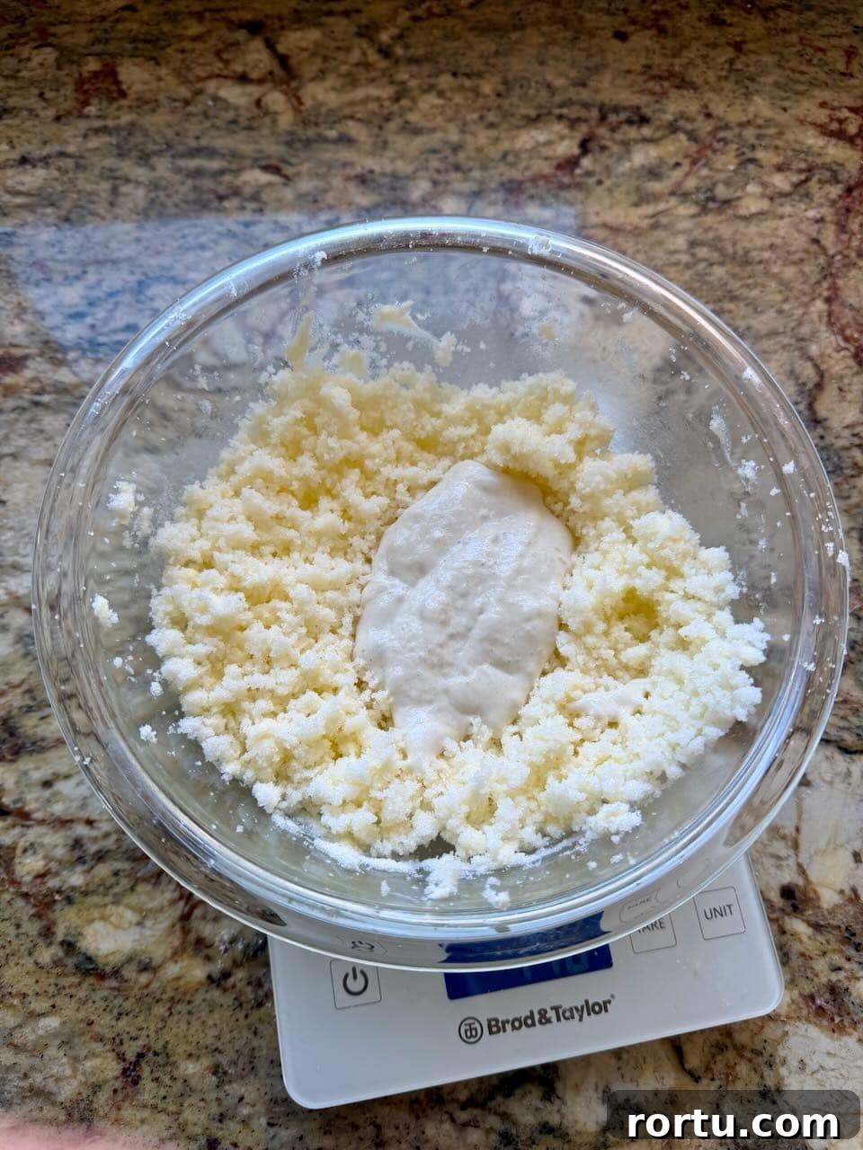 Crumbly butter and sugar mixture in a glass bowl with a dollop of sourdough discard on top.