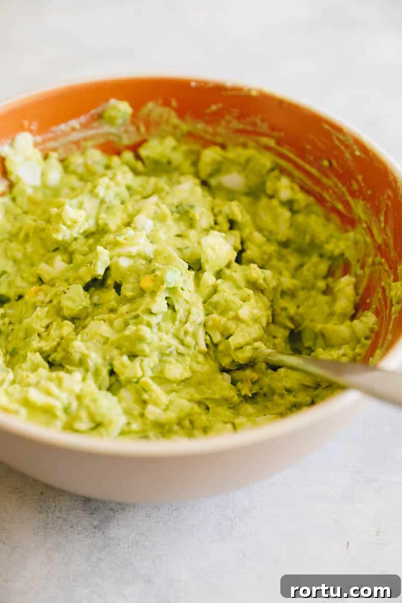 Creamy Avocado Egg Salad Recipe for Quick Lunch or Brunch 5 avocado egg salad in a large brown bowl with a spoon.