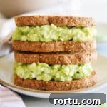 avocado egg salad on two sandwiches stacked on top of one another.