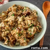 Cooked chicken and stuffing mixture topped with chopped herbs in a white bowl.