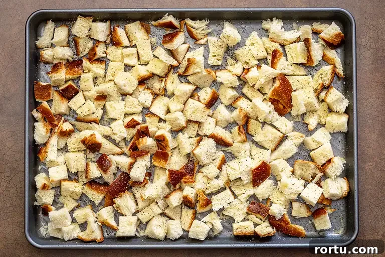 Cubed sourdough bread on baking sheet with seasonings.